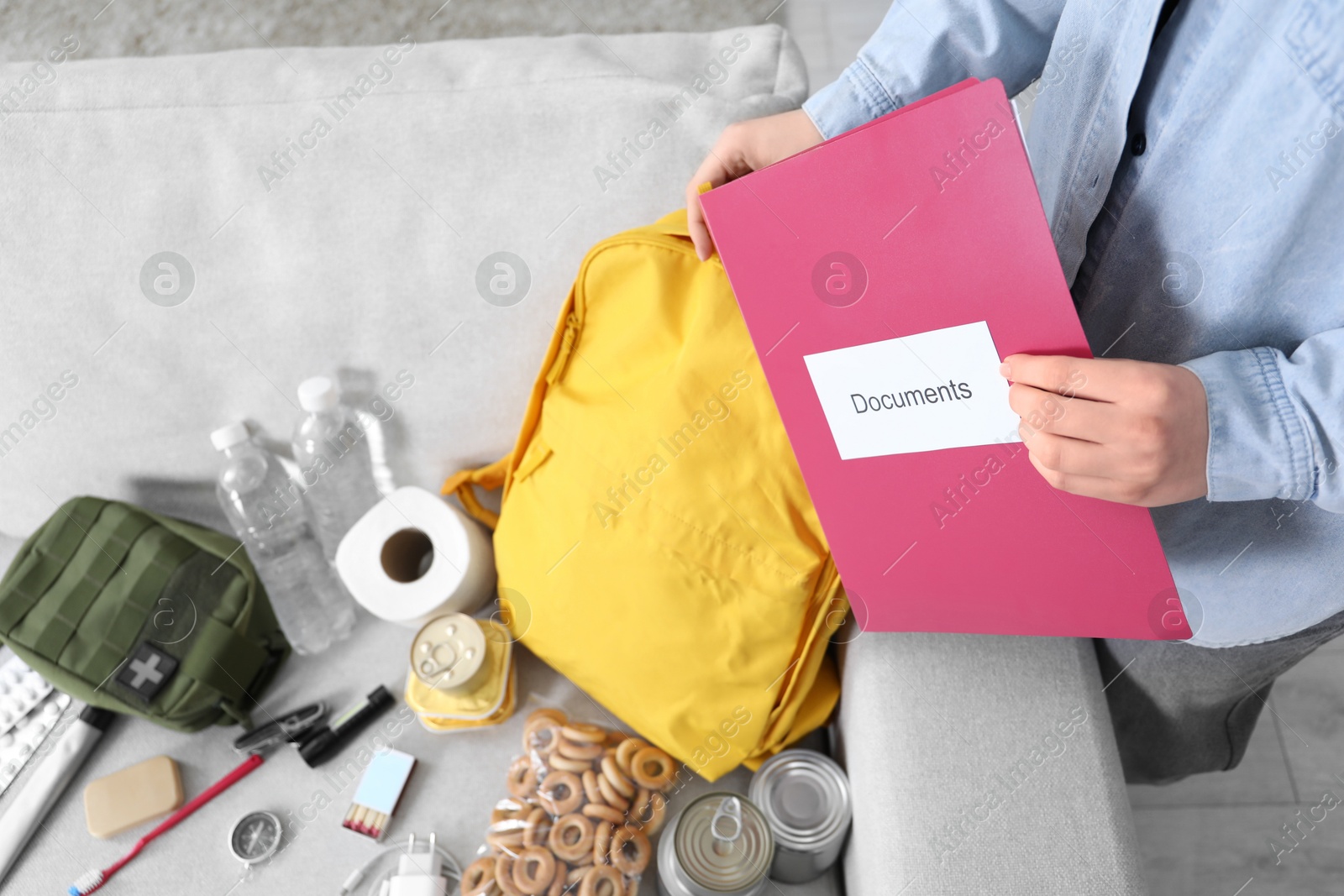 Survival kit. Woman putting documents into backpack indoors, closeup Photo of Survival kit. Woman putting documents into backpack indoors, closeup