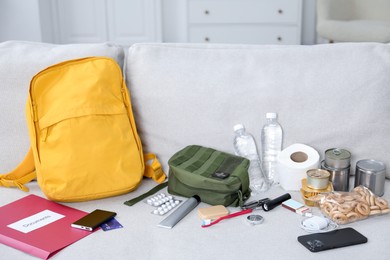 Photo of Survival kit. Different emergency supplies on sofa indoors