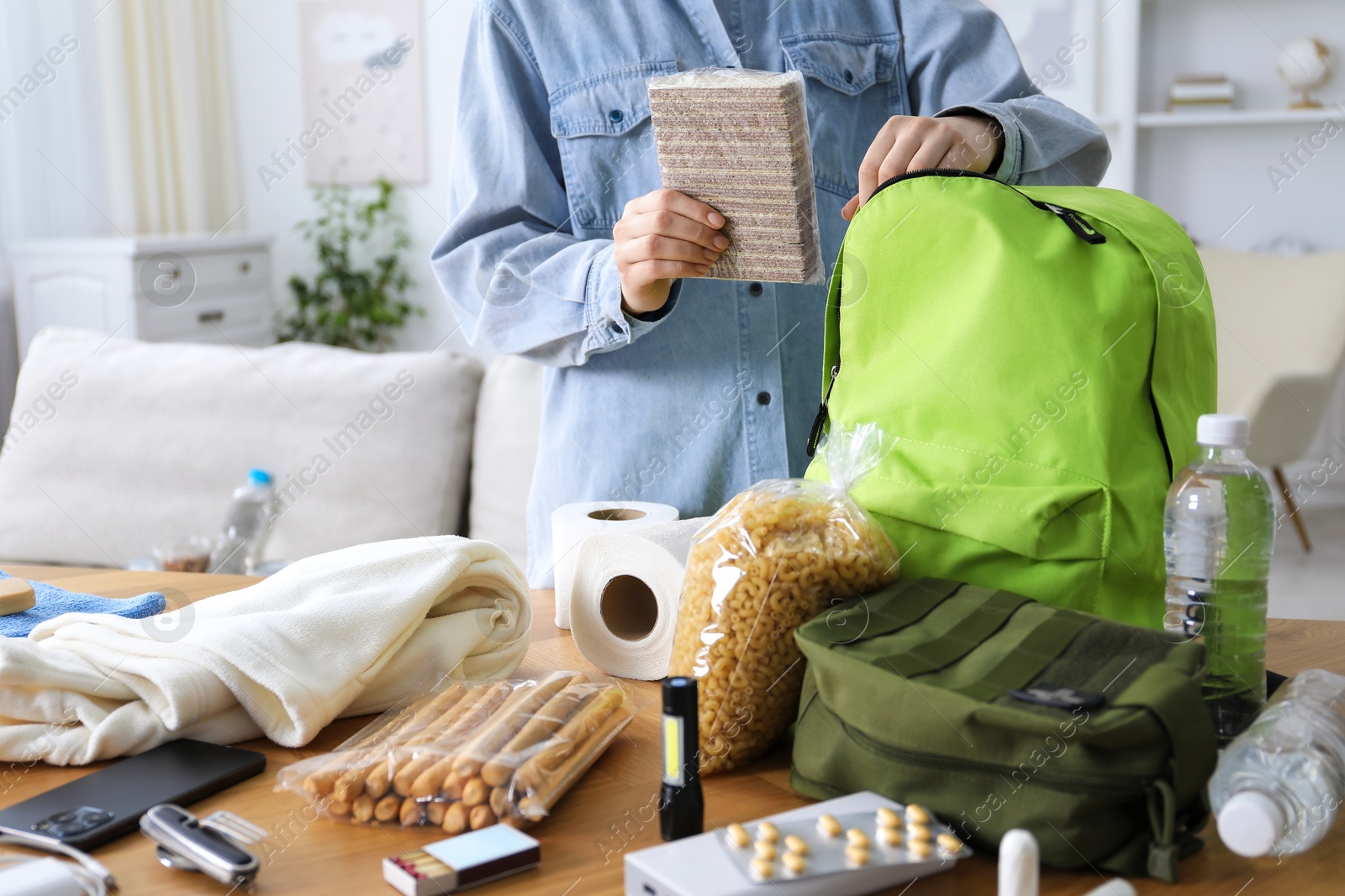 Survival kit. Woman packing different emergency supplies at wooden table indoors, closeup Photo of Survival kit. Woman packing different emergency supplies at wooden table indoors, closeup