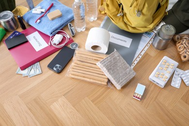 Photo of Survival kit. Different emergency supplies on wooden table indoors, above view