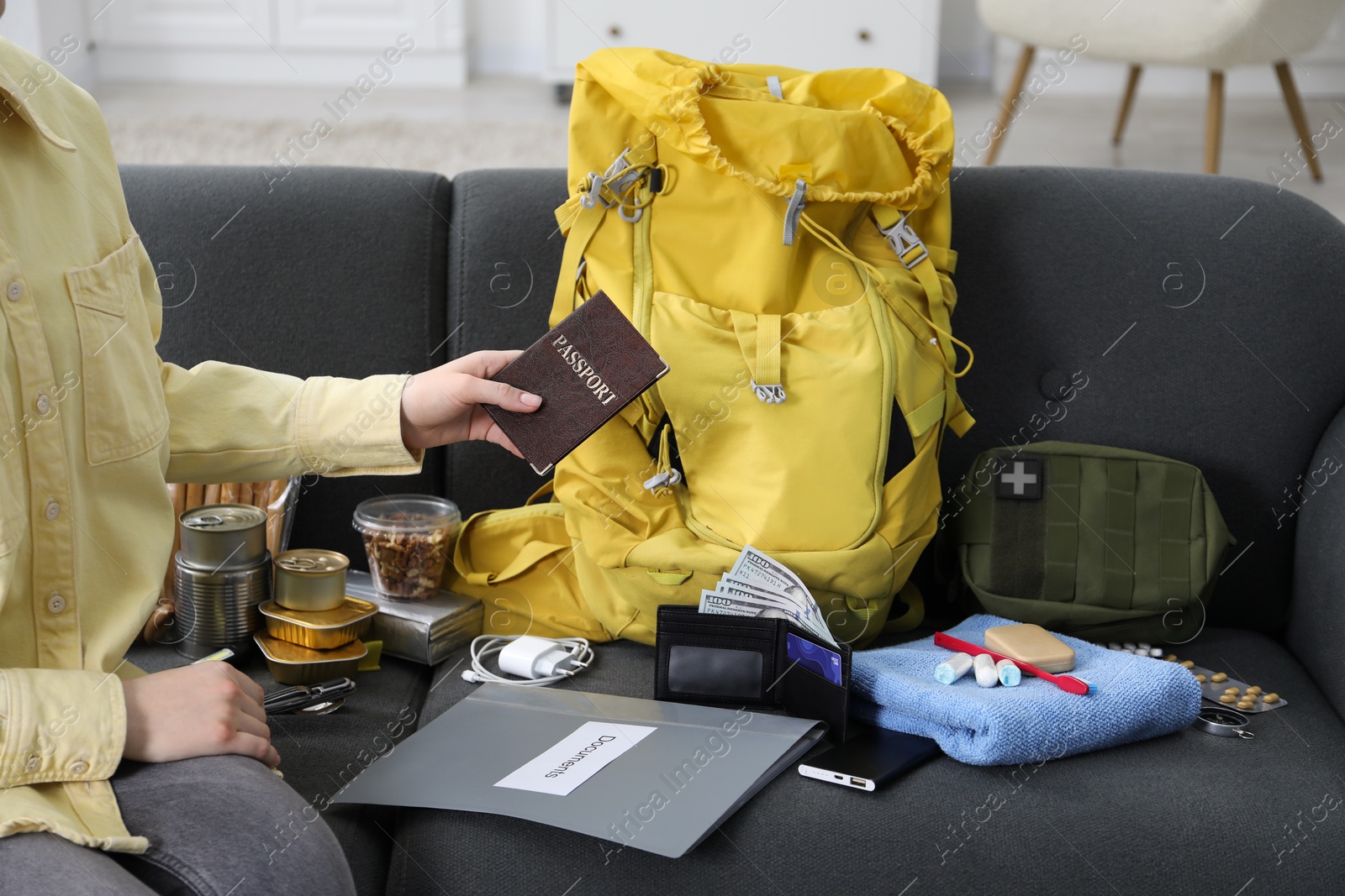 Survival kit. Woman packing different emergency supplies on sofa indoors, closeup Photo of Survival kit. Woman packing different emergency supplies on sofa indoors, closeup