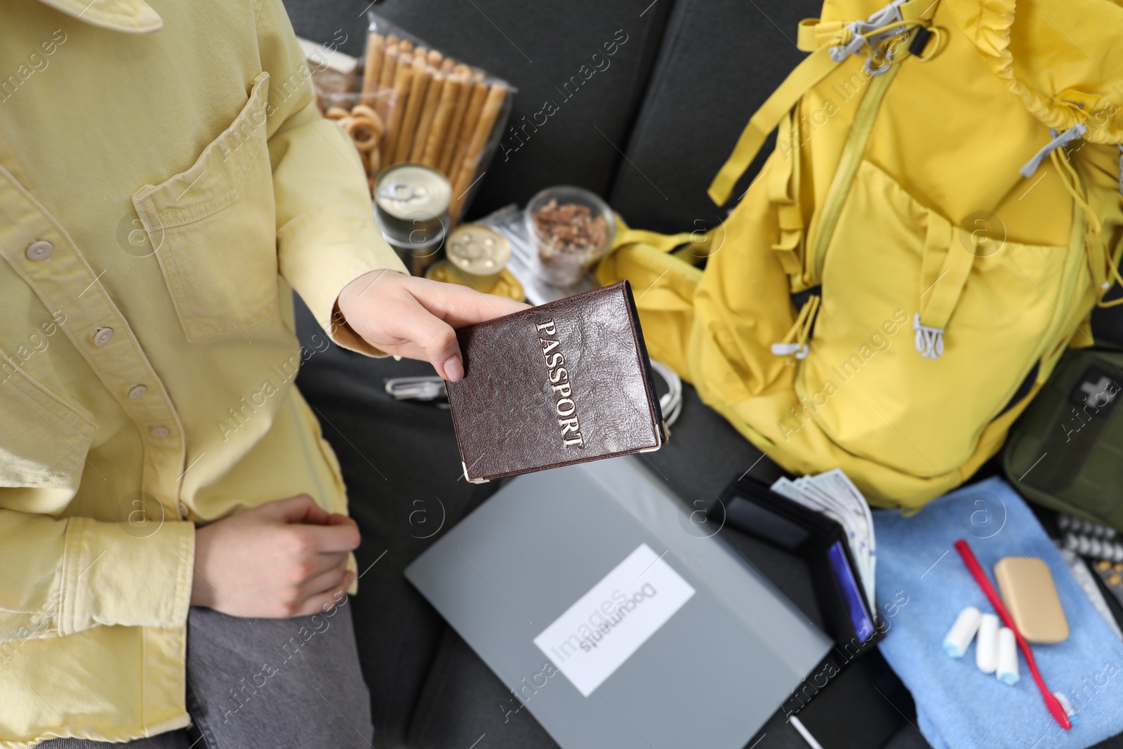 Survival kit. Woman packing different emergency supplies on sofa indoors, above view Photo of Survival kit. Woman packing different emergency supplies on sofa indoors, above view