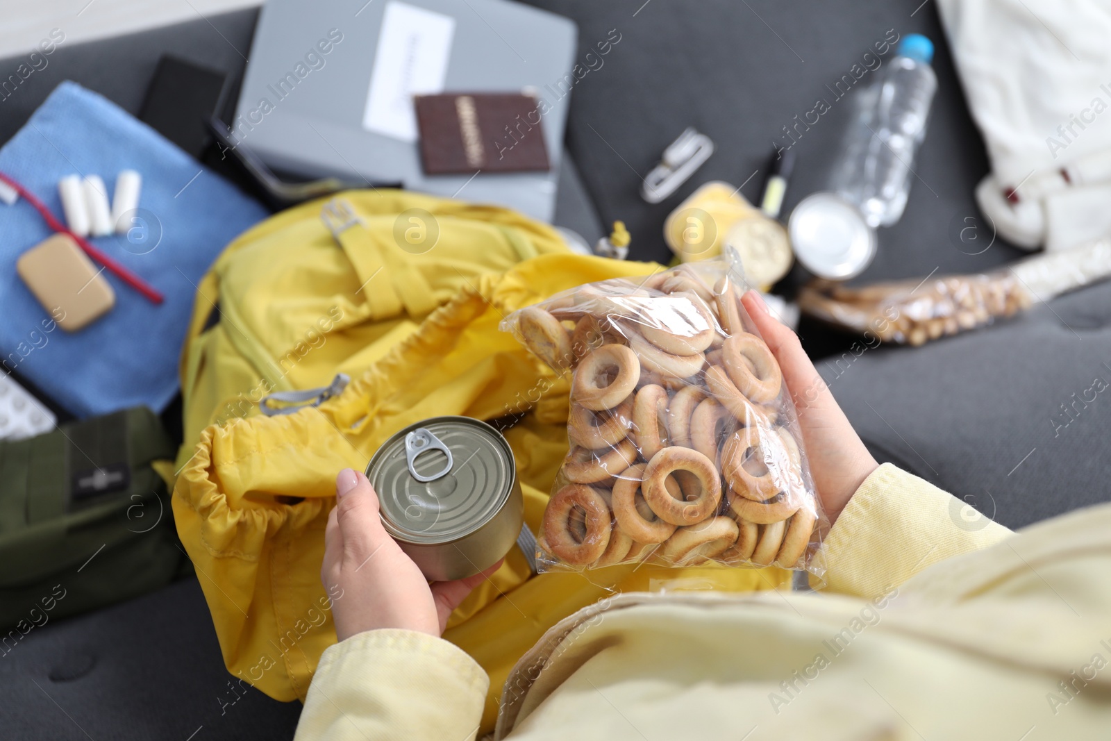 Survival kit. Woman putting food into backpack on indoors, top view Photo of Survival kit. Woman putting food into backpack on indoors, top view