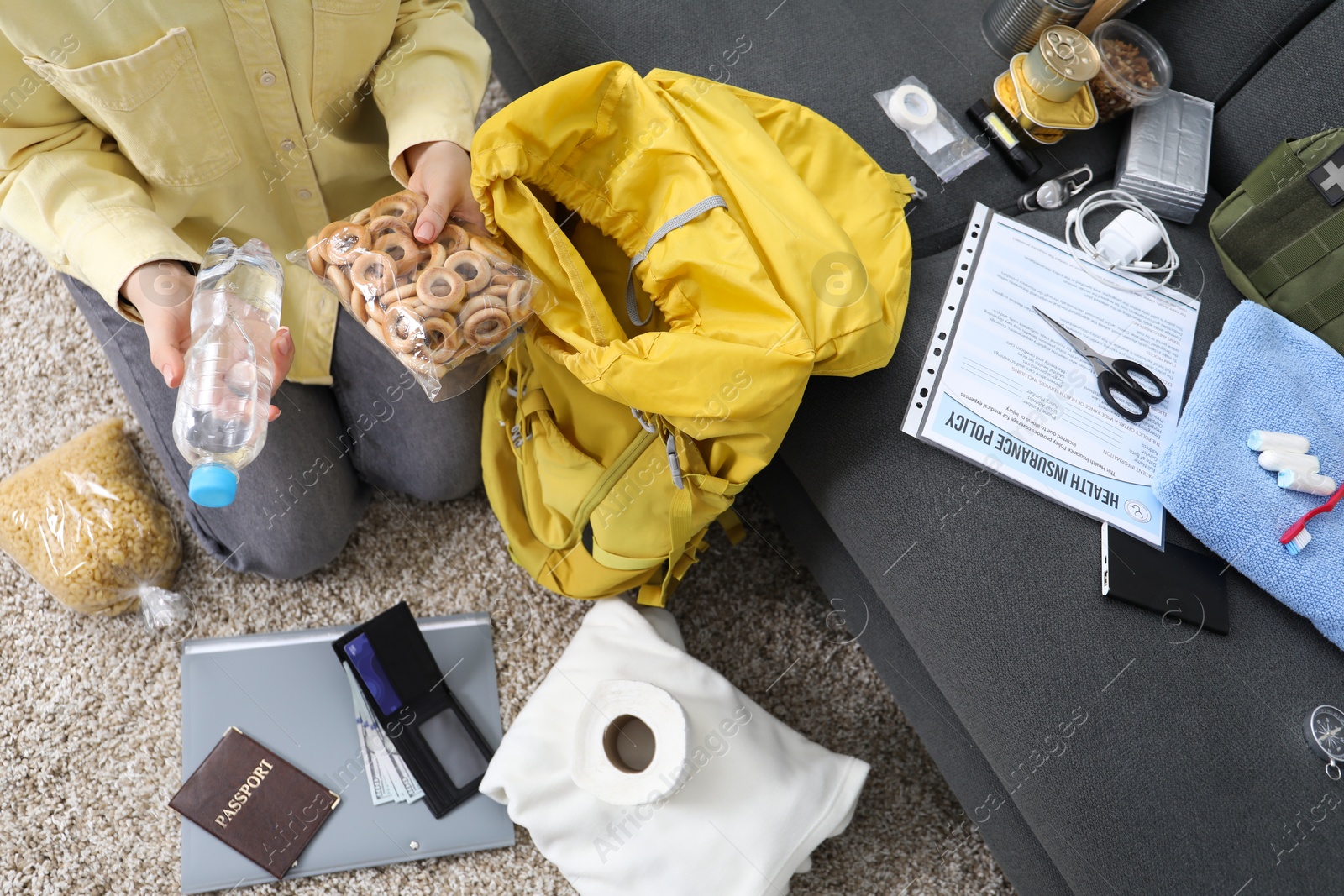 Survival kit. Woman packing different emergency supplies on floor indoors, above view Photo of Survival kit. Woman packing different emergency supplies on floor indoors, above view