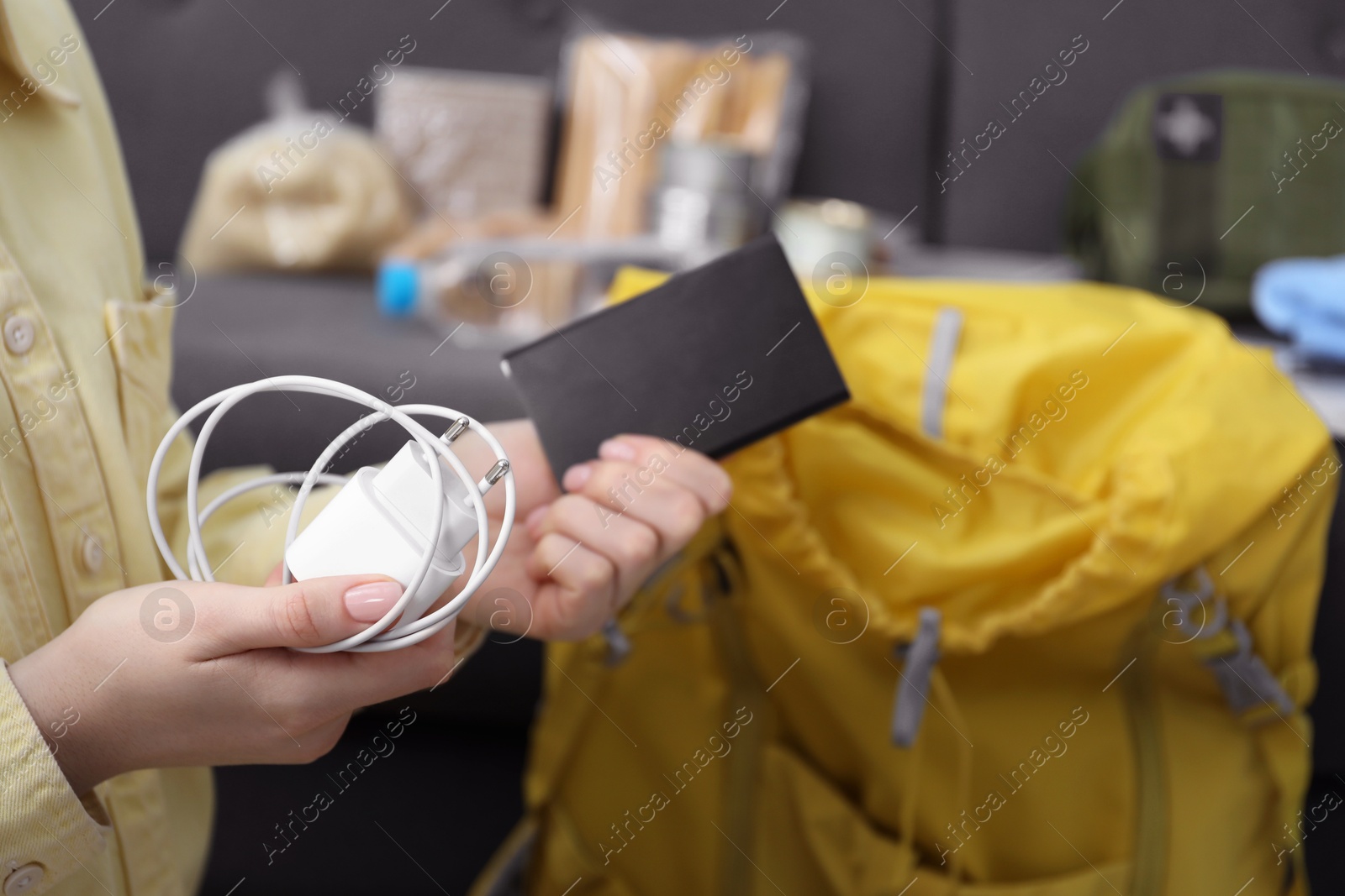 Survival kit. Woman packing different emergency supplies into backpack indoors, closeup Photo of Survival kit. Woman packing different emergency supplies into backpack indoors, closeup
