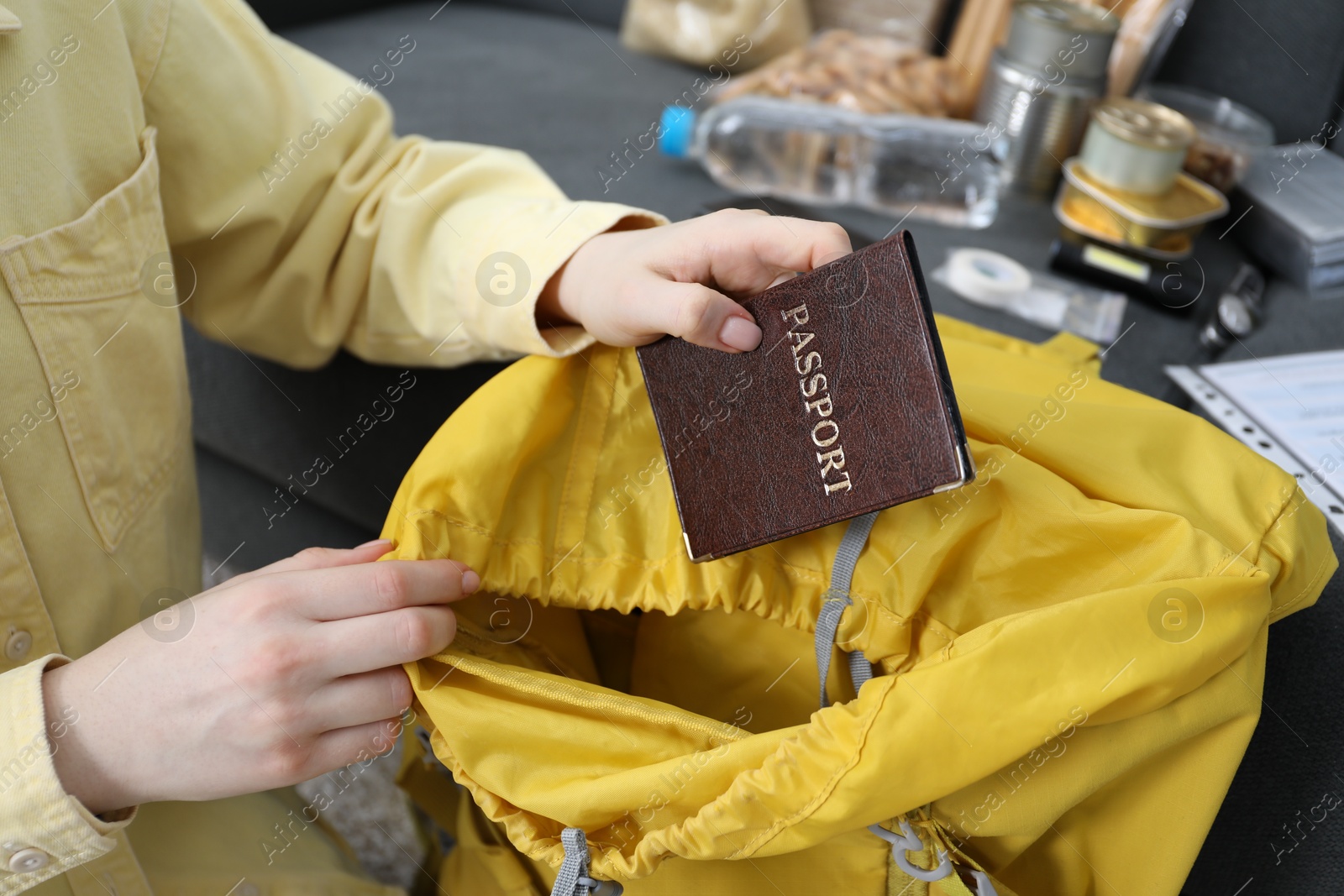 Survival kit. Woman putting passport into backpack indoors, closeup Photo of Survival kit. Woman putting passport into backpack indoors, closeup