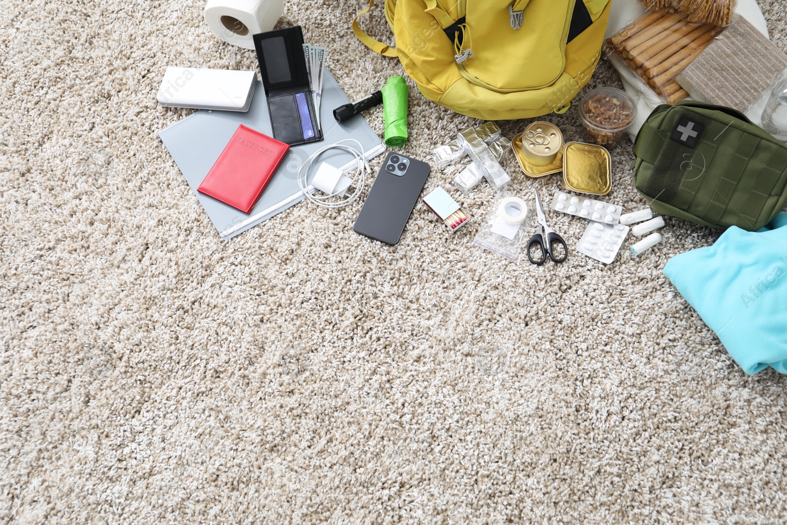 Survival kit. Different emergency supplies on floor indoors, above view. Space for text Photo of Survival kit. Different emergency supplies on floor indoors, above view. Space for text
