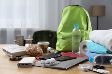 Photo of Survival kit. Different emergency supplies on wooden table indoors