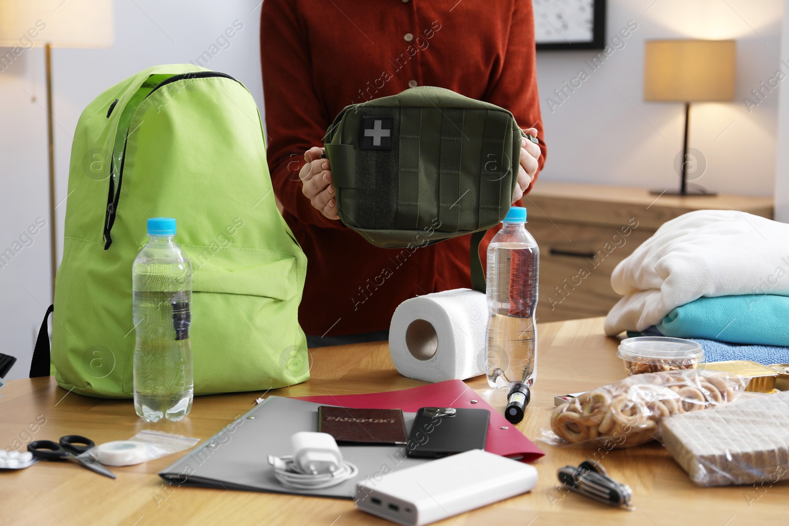 Survival kit. Woman packing different emergency supplies at wooden table indoors, closeup Photo of Survival kit. Woman packing different emergency supplies at wooden table indoors, closeup