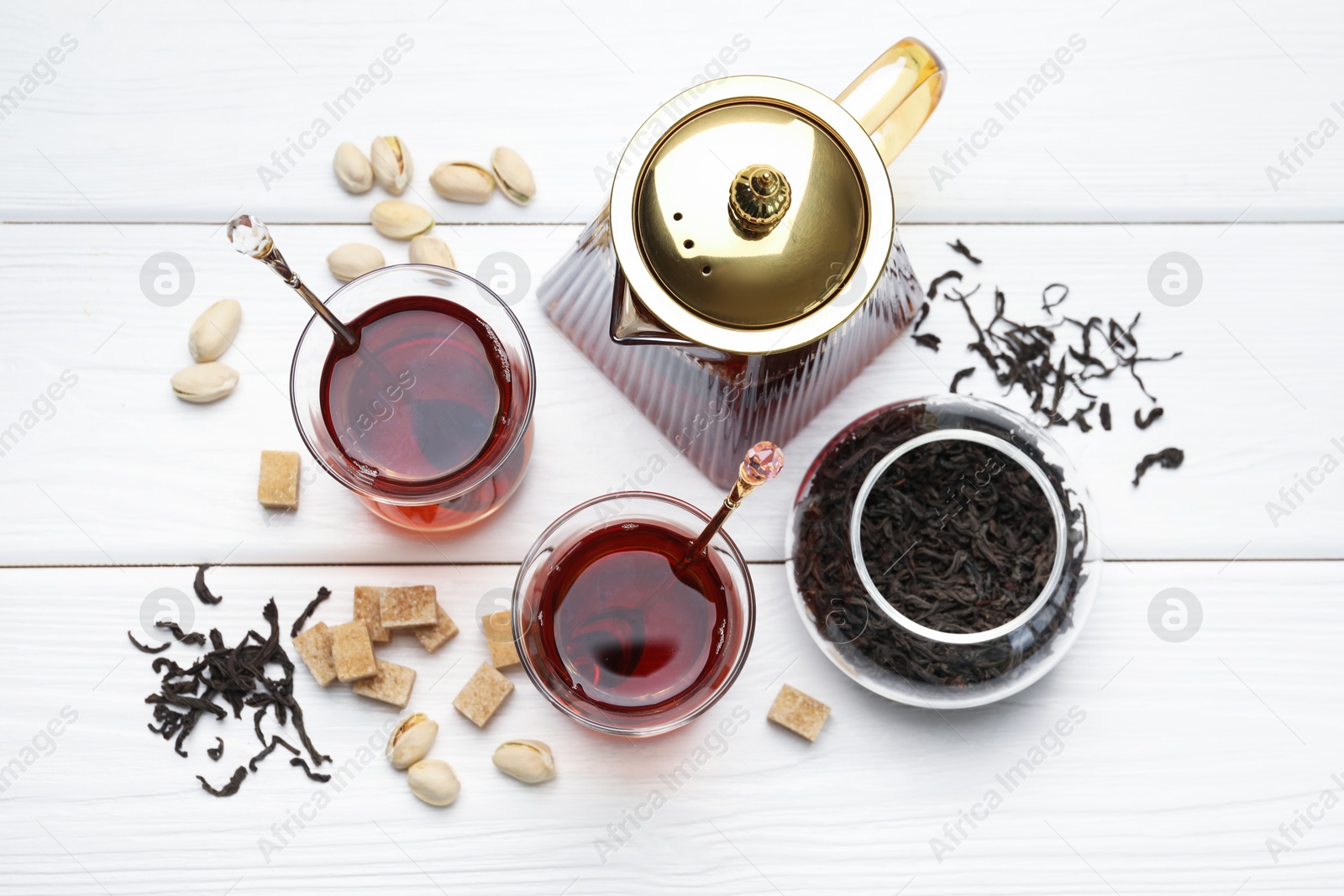 Tasty Turkish tea, sugar and pistachios on white wooden table, flat lay Photo of Tasty Turkish tea, sugar and pistachios on white wooden table, flat lay