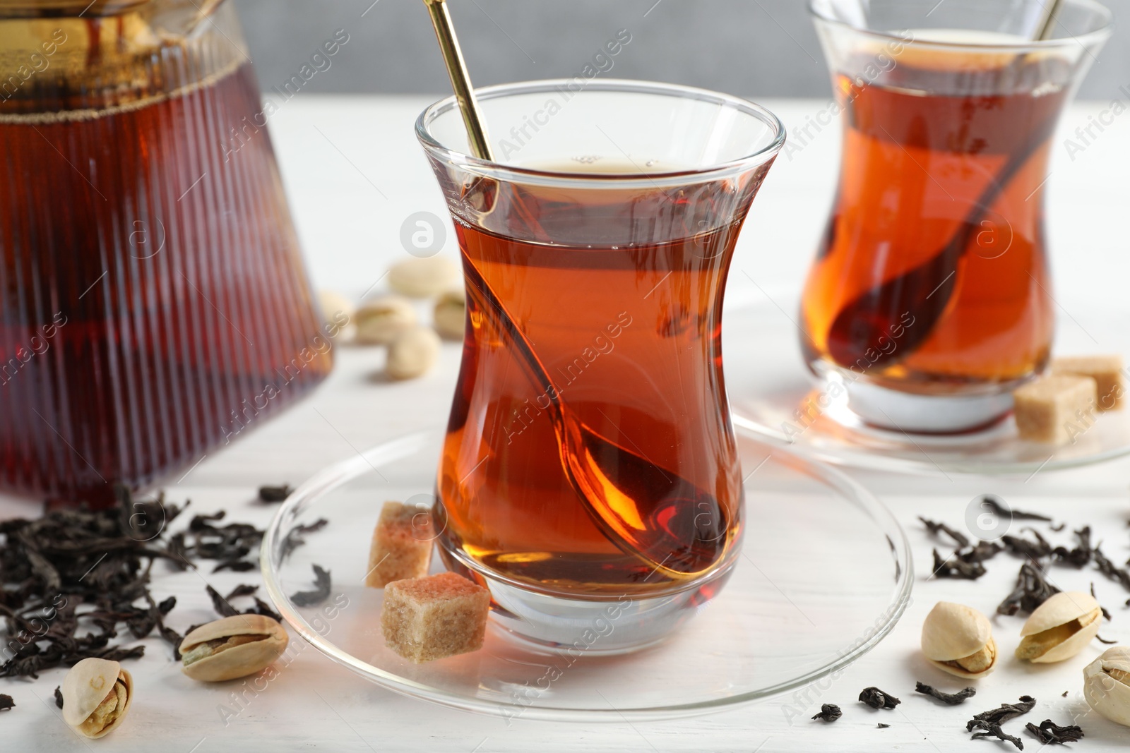 Tasty Turkish tea, sugar and pistachios on white wooden table, closeup Photo of Tasty Turkish tea, sugar and pistachios on white wooden table, closeup