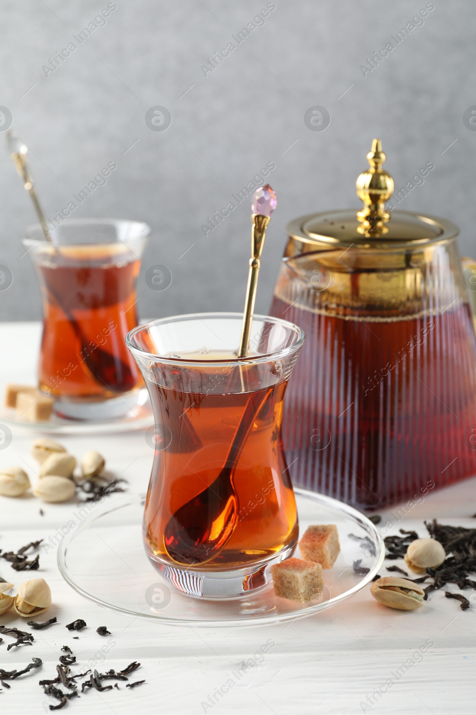 Tasty Turkish tea, sugar and pistachios on white wooden table Photo of Tasty Turkish tea, sugar and pistachios on white wooden table