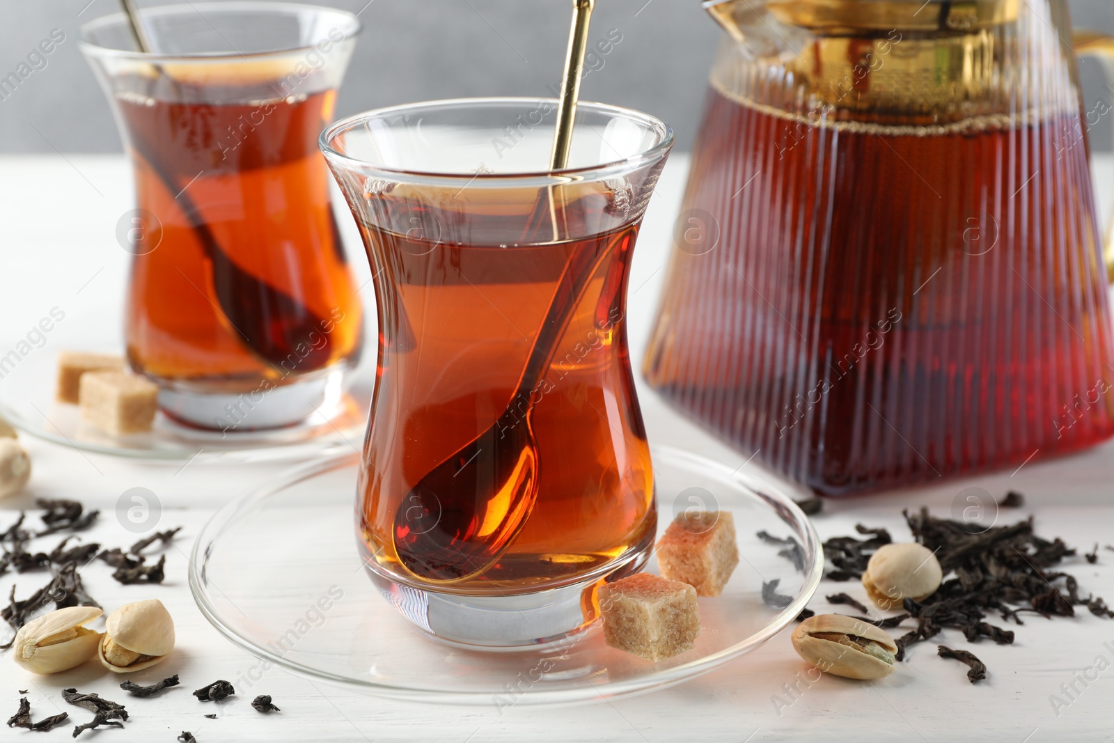 Tasty Turkish tea, sugar and pistachios on white wooden table, closeup Photo of Tasty Turkish tea, sugar and pistachios on white wooden table, closeup