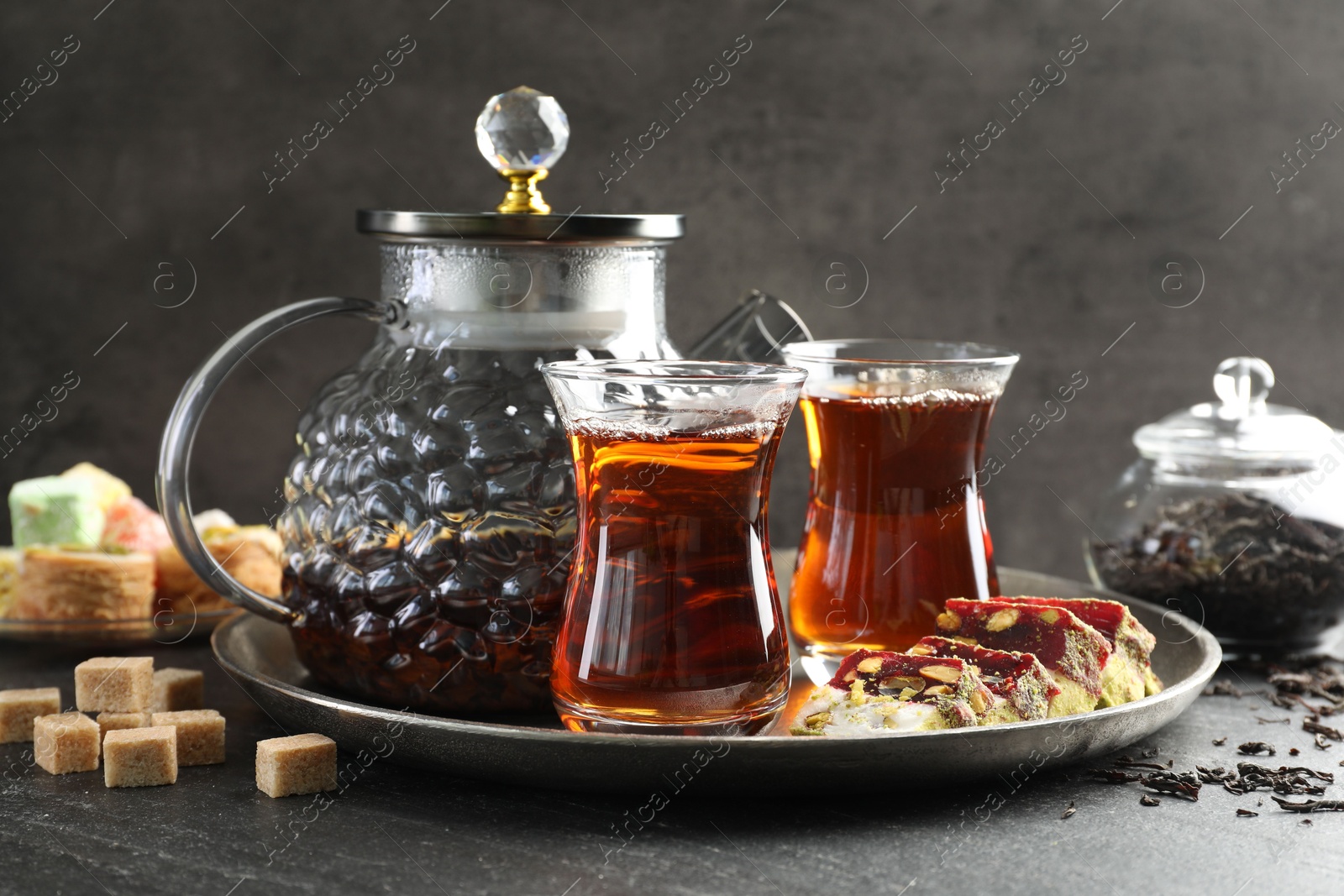 Tasty Turkish tea and delight on black table Photo of Tasty Turkish tea and delight on black table