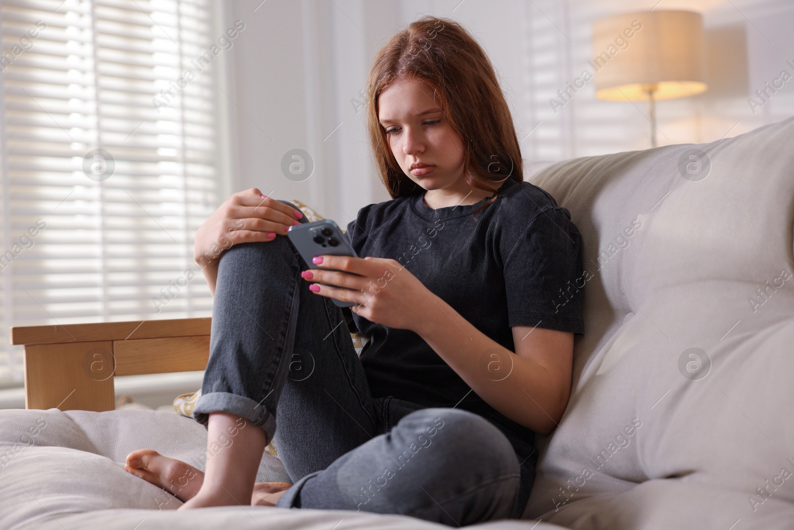 Sad teenage girl on sofa at home Photo of Sad teenage girl on sofa at home
