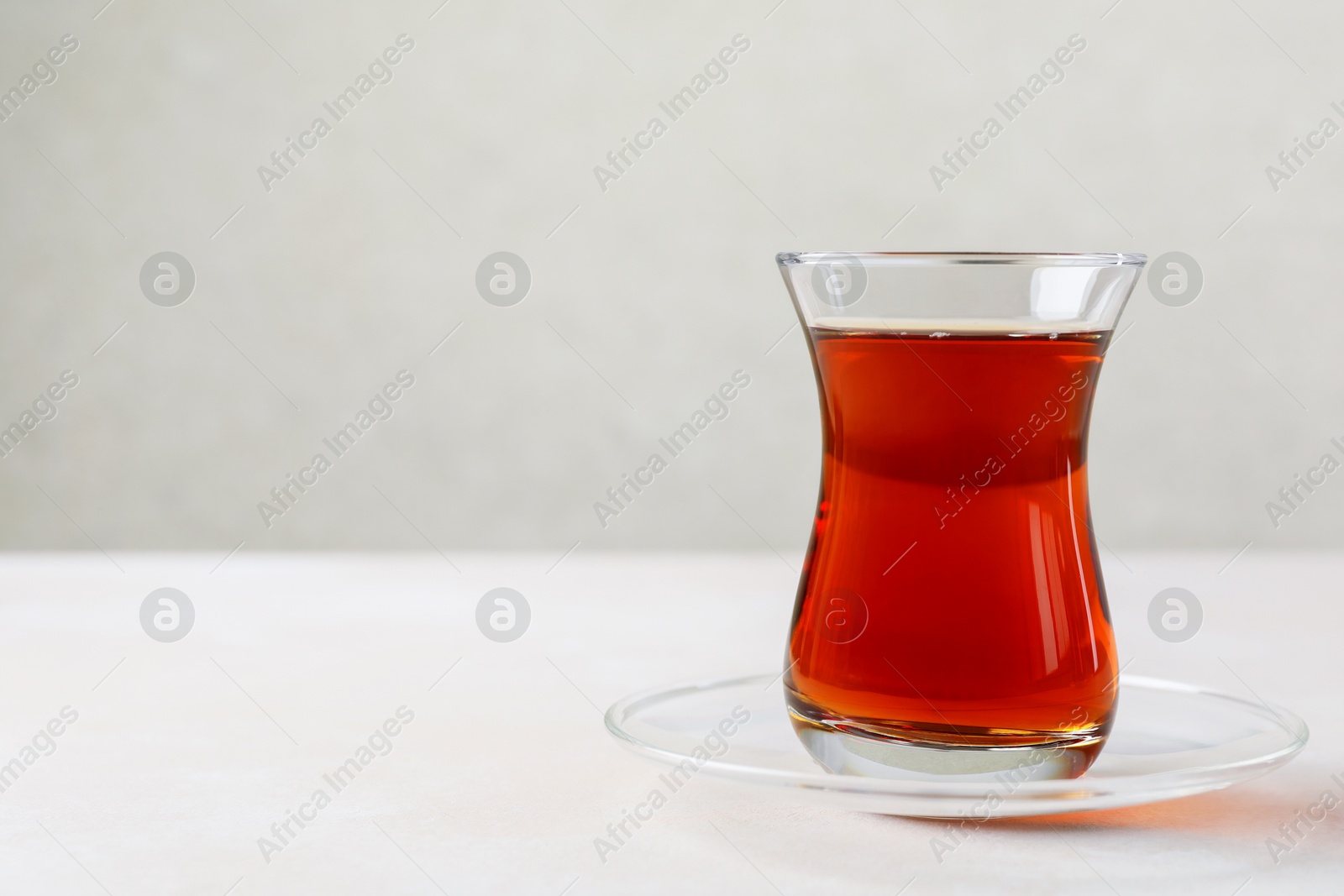 Traditional Turkish tea in glass cup on white table, closeup. Space for text Photo of Traditional Turkish tea in glass cup on white table, closeup. Space for text