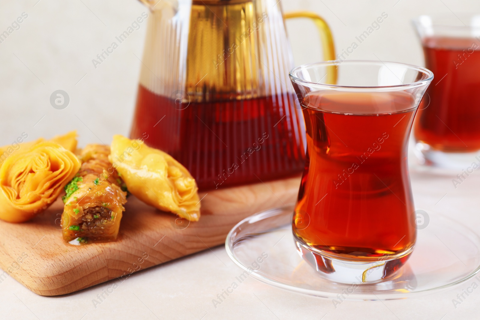 Traditional Turkish tea in glass cups, teapot and fresh baklava on white table, closeup Photo of Traditional Turkish tea in glass cups, teapot and fresh baklava on white table, closeup
