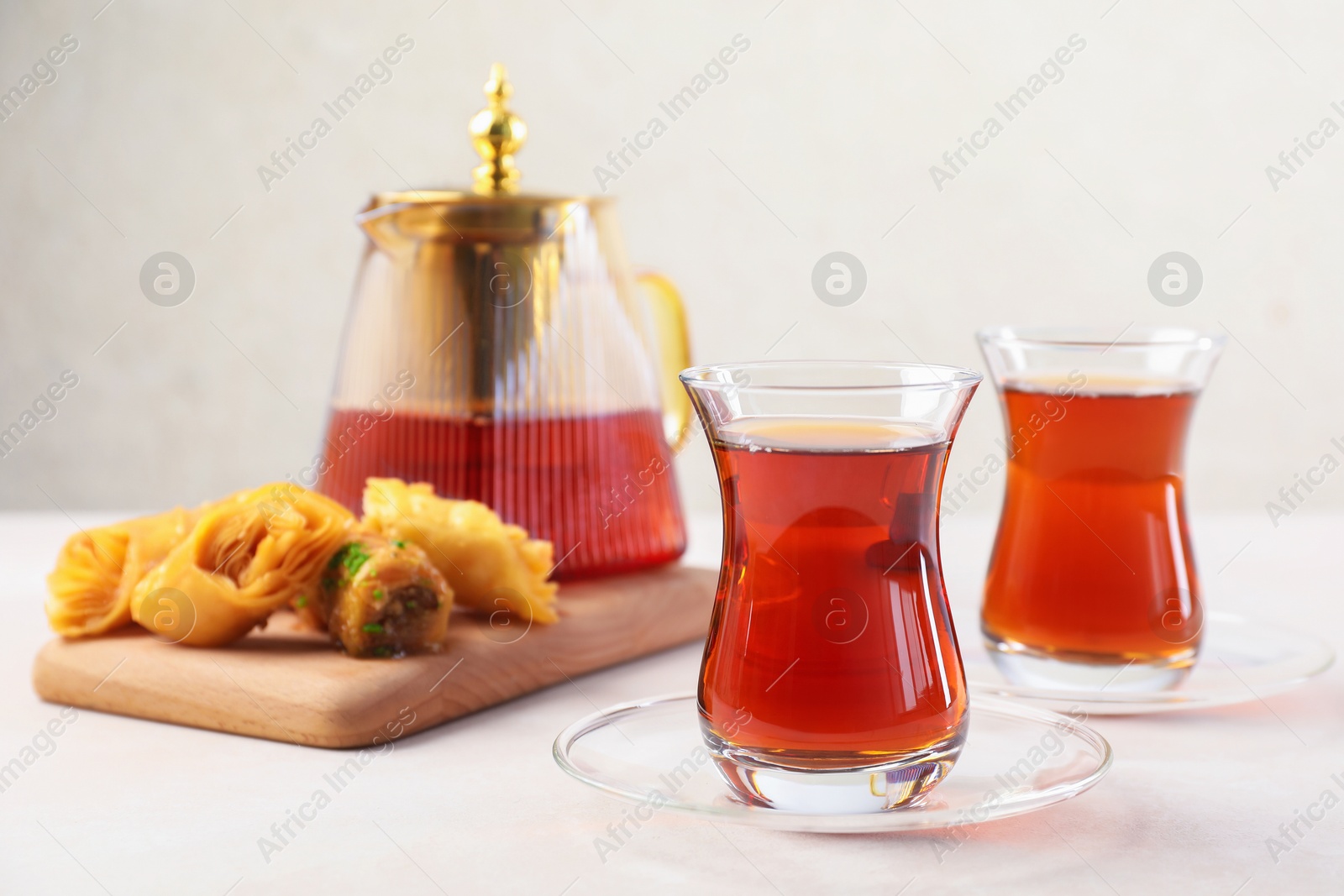 Traditional Turkish tea in glass cups, teapot and fresh baklava on white table, closeup Photo of Traditional Turkish tea in glass cups, teapot and fresh baklava on white table, closeup