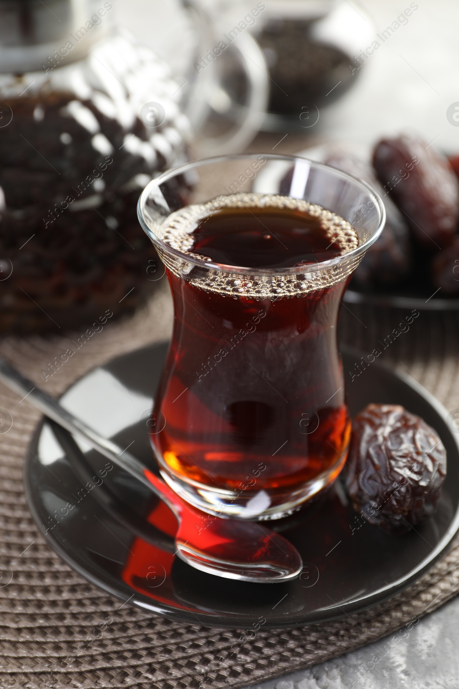 Traditional Turkish tea in glass cup and dates on table, closeup Photo of Traditional Turkish tea in glass cup and dates on table, closeup