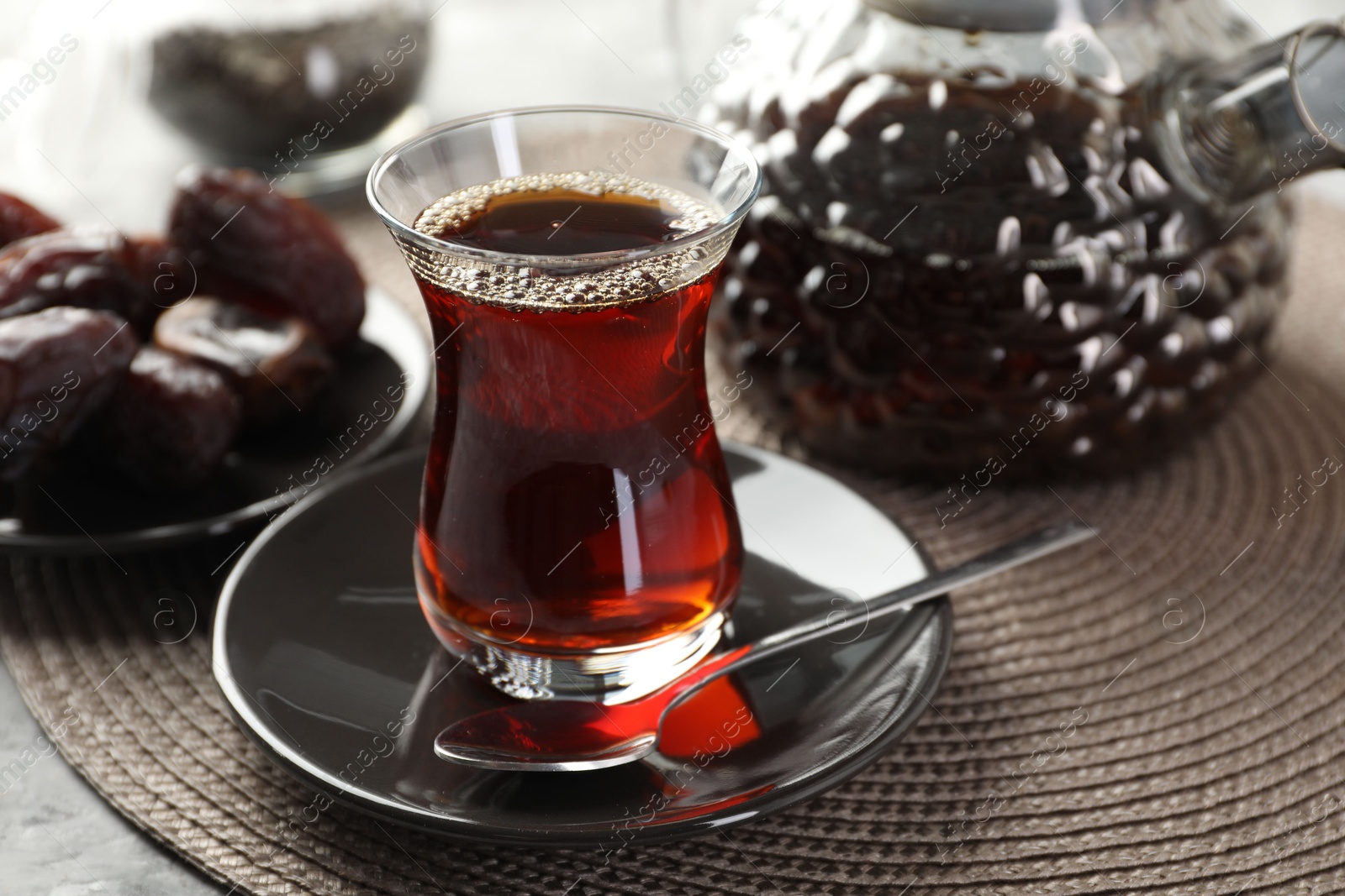 Traditional Turkish tea in glass cup, teapot and dates on table, closeup Photo of Traditional Turkish tea in glass cup, teapot and dates on table, closeup