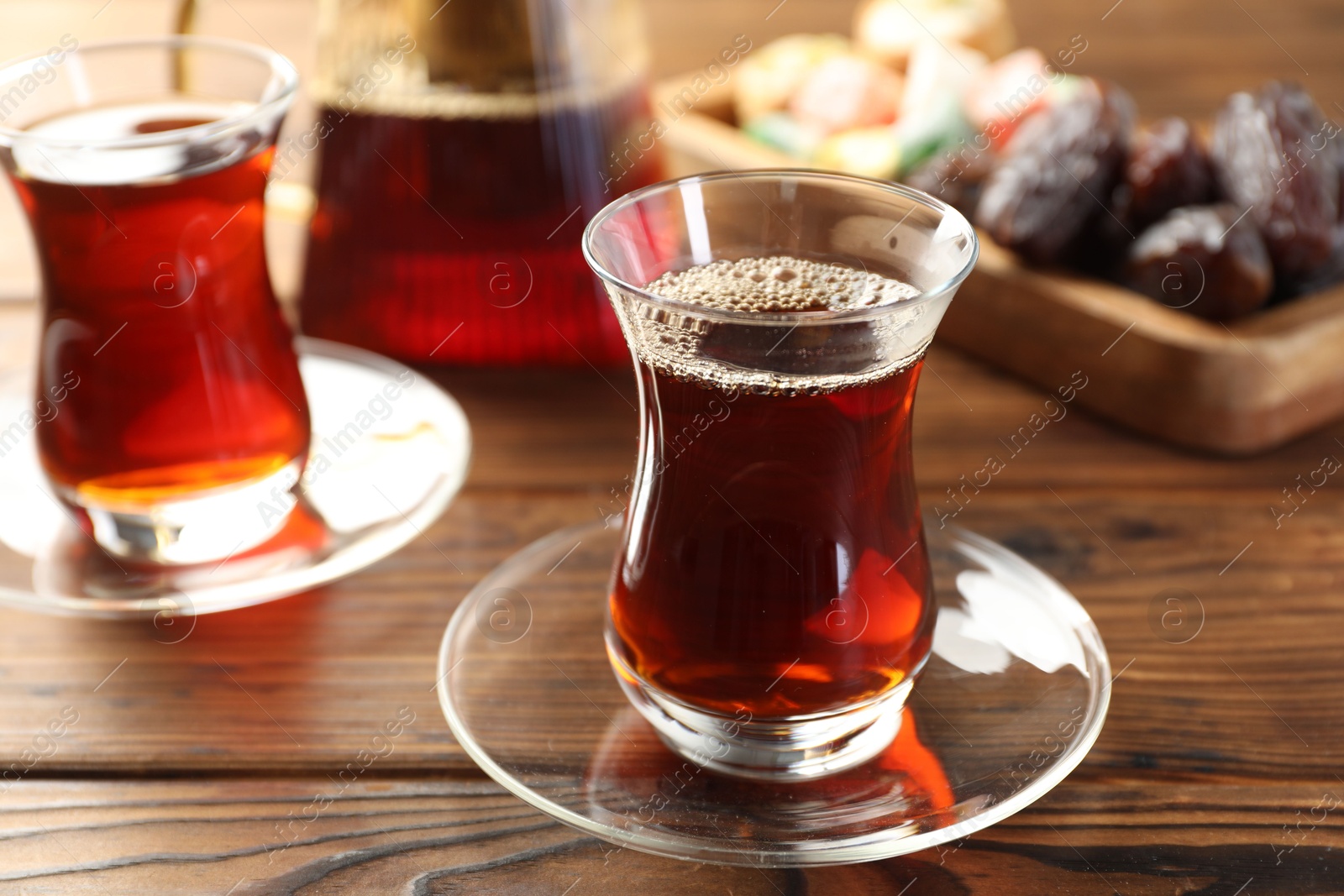 Traditional Turkish tea in glass cups, teapot and sweets on wooden table, closeup Photo of Traditional Turkish tea in glass cups, teapot and sweets on wooden table, closeup