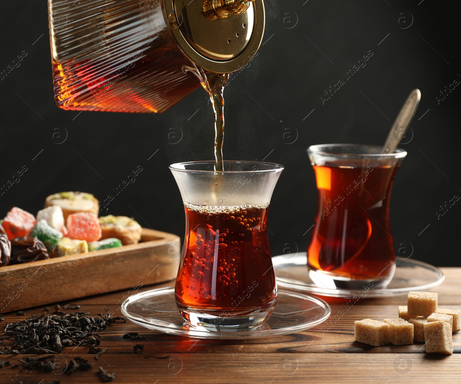 Pouring Turkish tea into glass cup at wooden table, closeup Photo of Pouring Turkish tea into glass cup at wooden table, closeup