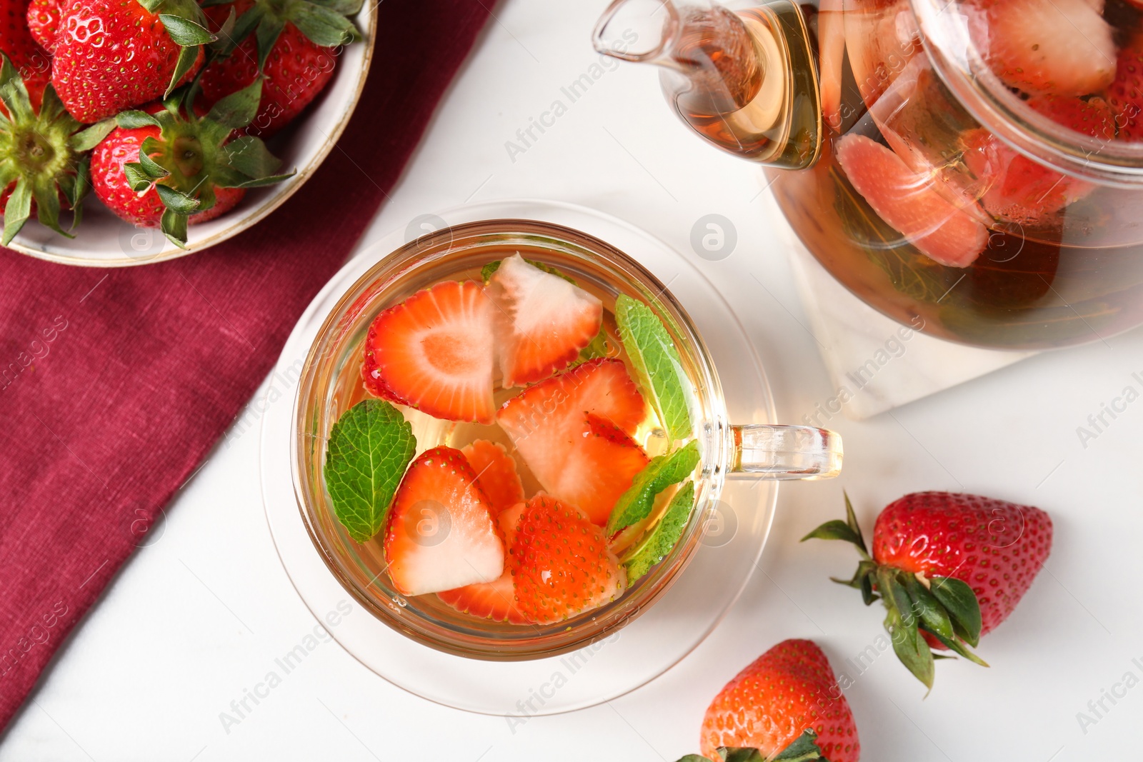 Aromatic fruit tea with strawberries and mint on white table, flat lay Photo of Aromatic fruit tea with strawberries and mint on white table, flat lay