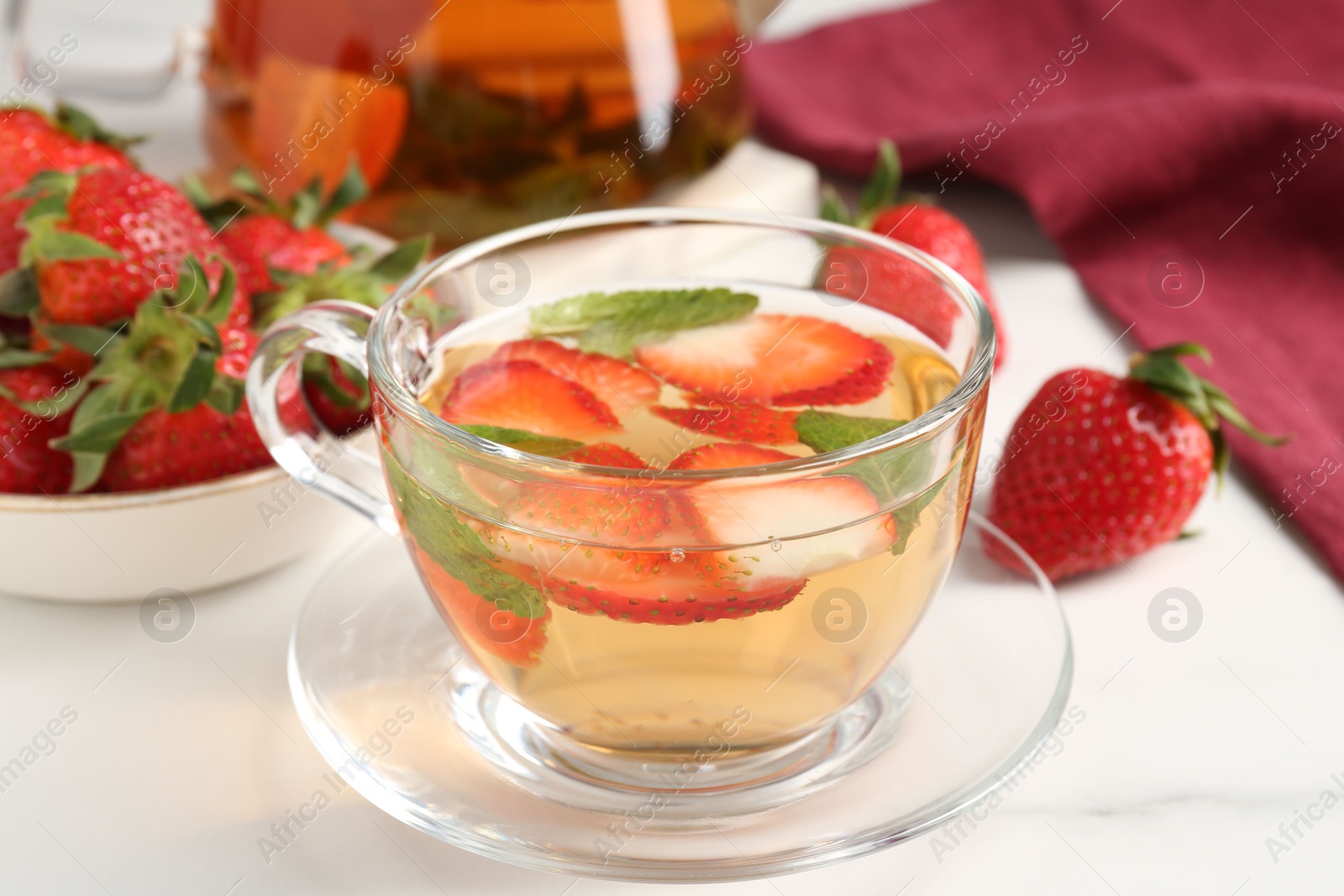 Photo of Aromatic fruit tea with strawberries and mint on white marble table, closeup