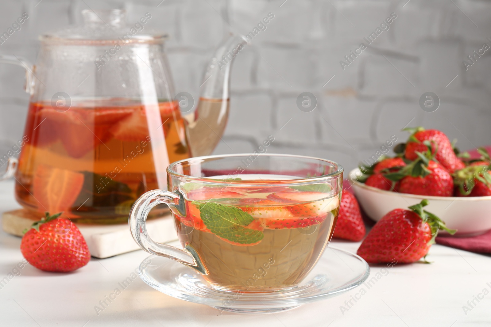 Aromatic fruit tea, strawberries and mint on white table, closeup Photo of Aromatic fruit tea, strawberries and mint on white table, closeup