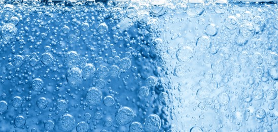 Image of Soda water with bubbles and ice cube as background, closeup