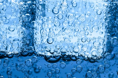 Image of Soda water with bubbles and ice cubes as background, closeup