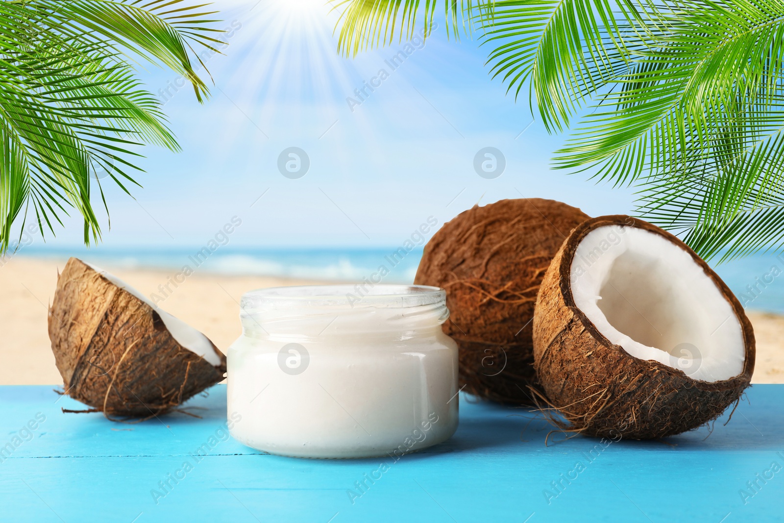 Cooking oil in jar and coconuts on blue table against beach Image of Cooking oil in jar and coconuts on blue table against beach