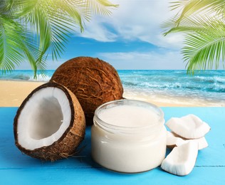 Image of Cooking oil in jar and coconuts on blue table against beach