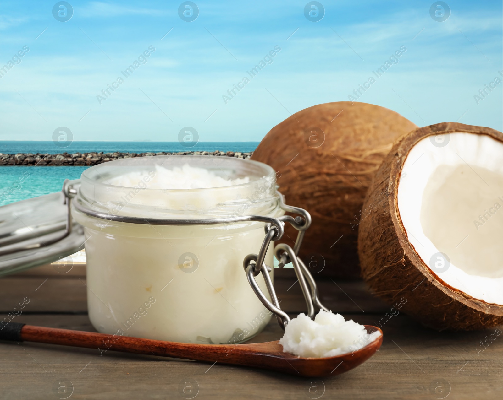 Cooking oil in jar and coconuts on wooden table against beach Image of Cooking oil in jar and coconuts on wooden table against beach