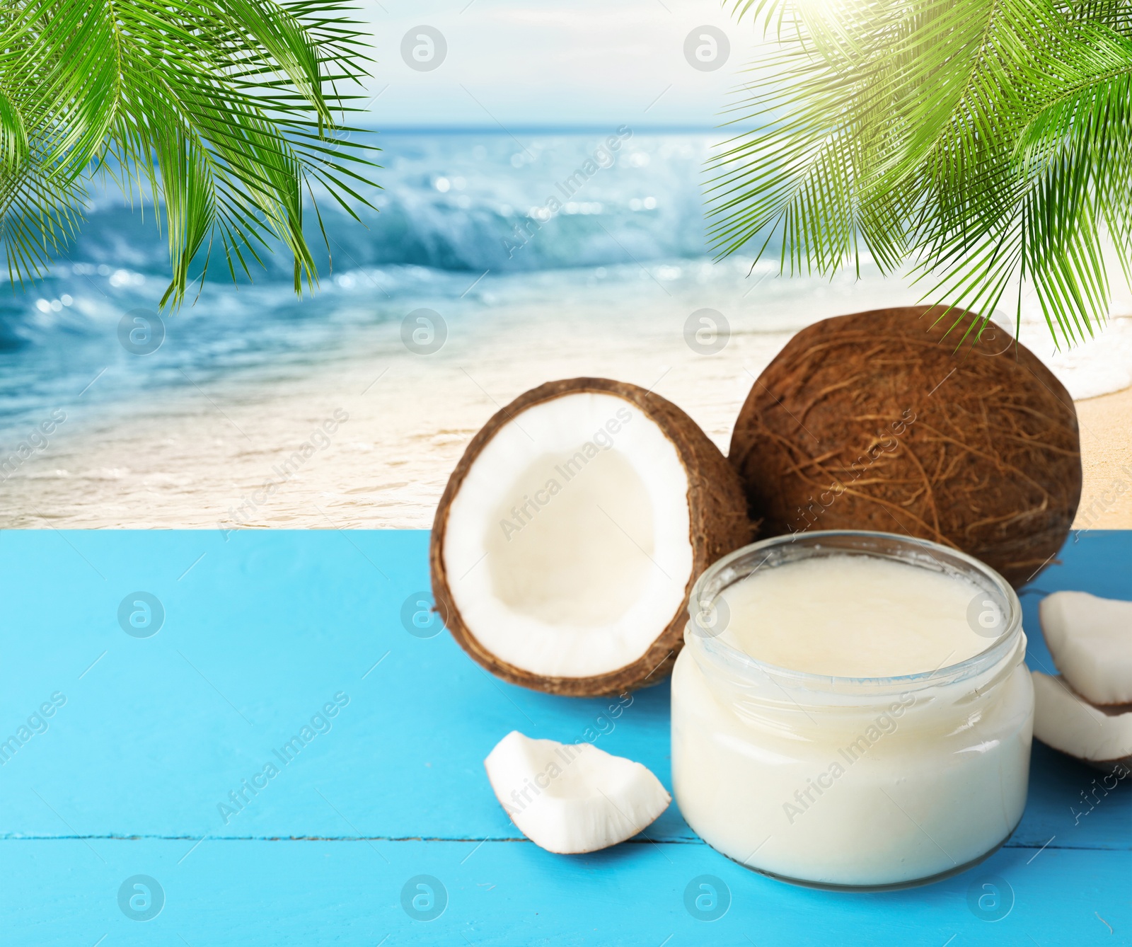 Cooking oil in jar and coconuts on blue table against beach. Space for text Image of Cooking oil in jar and coconuts on blue table against beach. Space for text