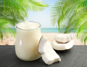 Image of Cooking oil in jar and coconut pieces on table against beach