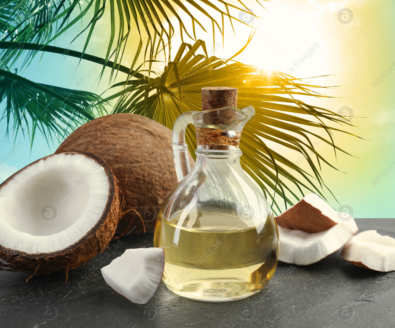Cooking oil in glass bottle and coconuts on table against palm leaves Image of Cooking oil in glass bottle and coconuts on table against palm leaves