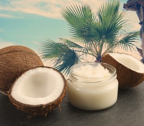 Image of Cooking oil in jar and coconuts on table against palm tree