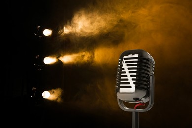Image of Vintage microphone on stage in smoke under spotlights. Singer's performance