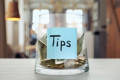 Image of Tips jar with money on white wooden table in cafe