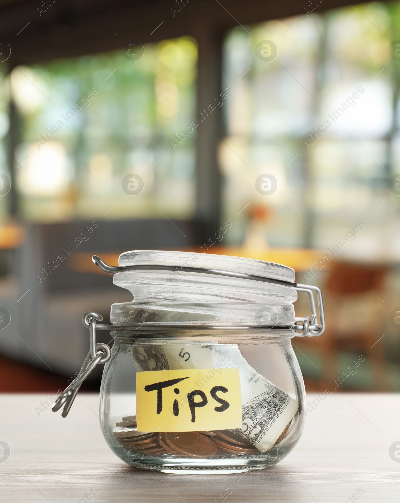 Tips jar with money on light wooden table in cafe Image of Tips jar with money on light wooden table in cafe
