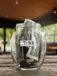 Image of Tips jar with money on wooden table in cafe