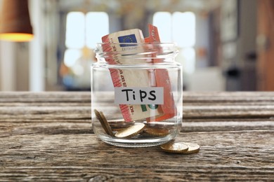 Image of Tips jar with money on wooden table in cafe