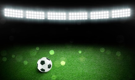 Image of Soccer ball on green grass at football stadium, space for text