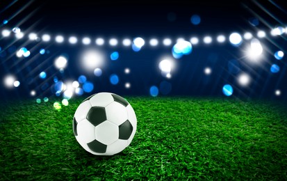 Image of Soccer ball on green grass at football stadium, space for text