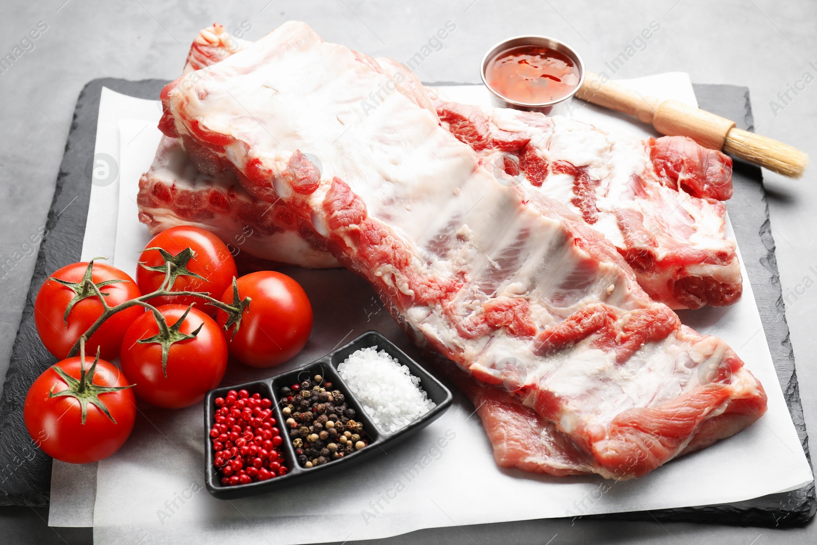 Raw pork ribs, tomatoes and spices on grey table, closeup Photo of Raw pork ribs, tomatoes and spices on grey table, closeup