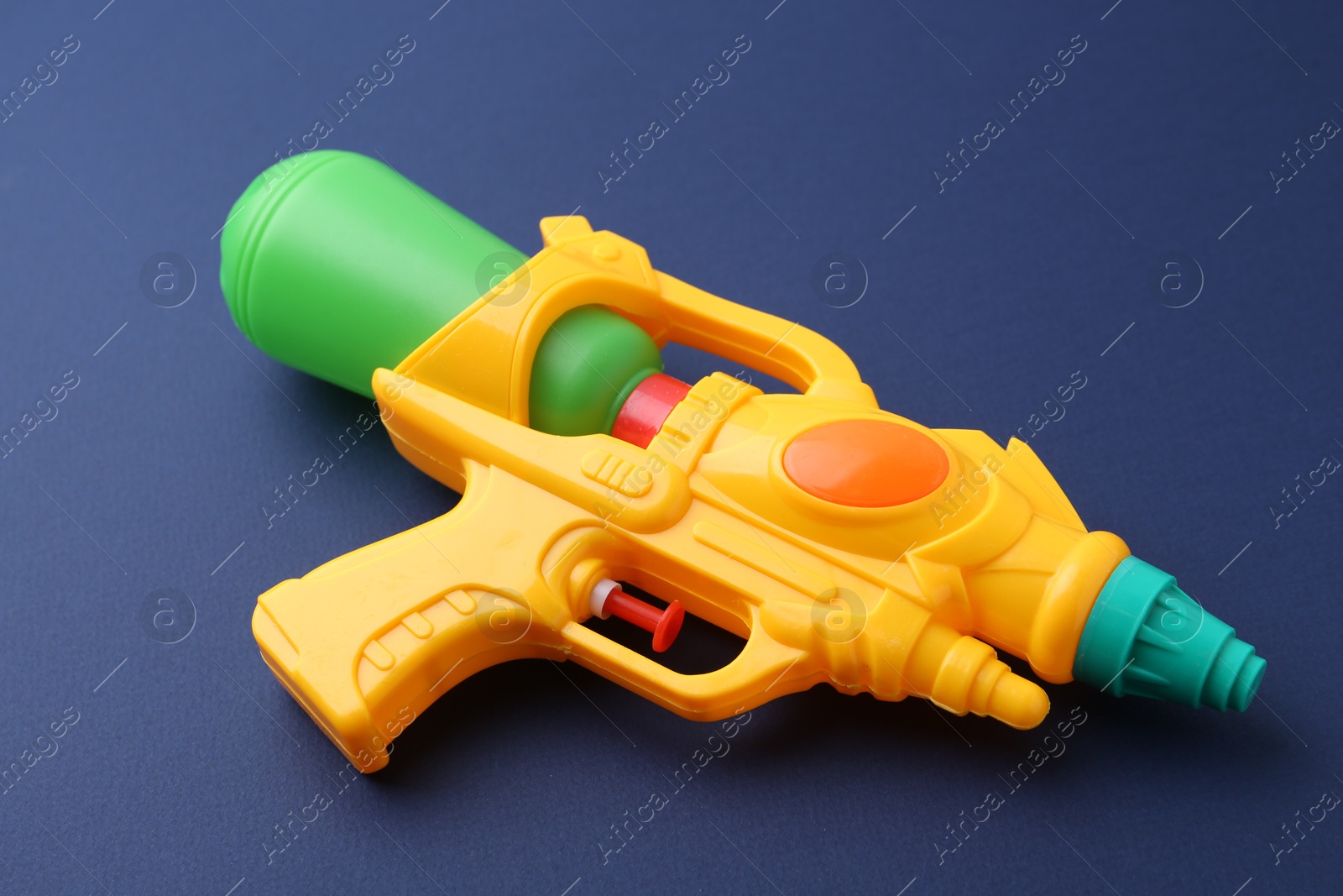 Bright plastic water gun on dark blue background, closeup Photo of Bright plastic water gun on dark blue background, closeup