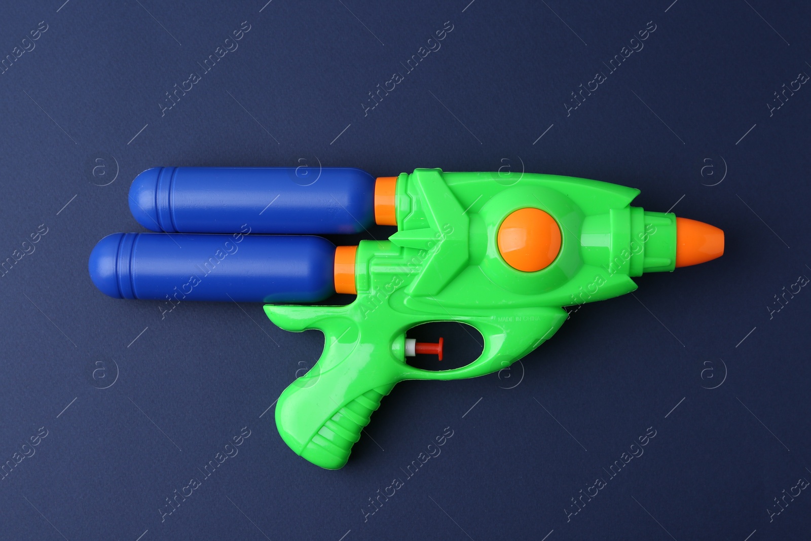 Bright plastic water gun on dark blue background, top view Photo of Bright plastic water gun on dark blue background, top view