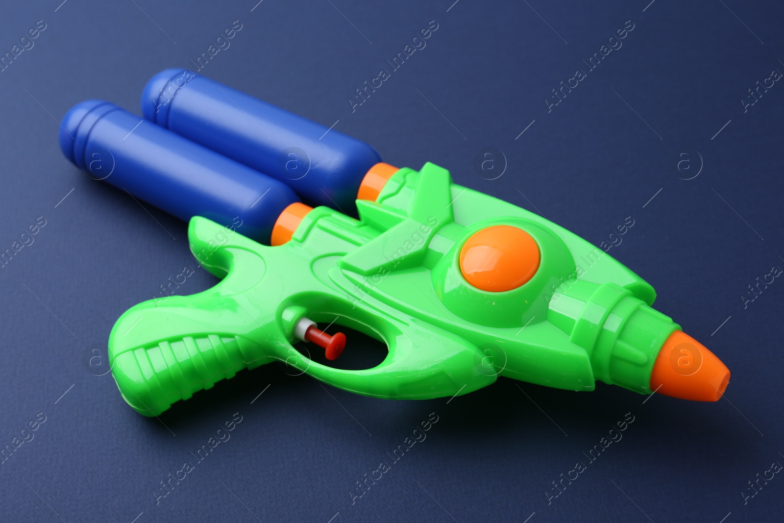 Bright plastic water gun on dark blue background, closeup Photo of Bright plastic water gun on dark blue background, closeup