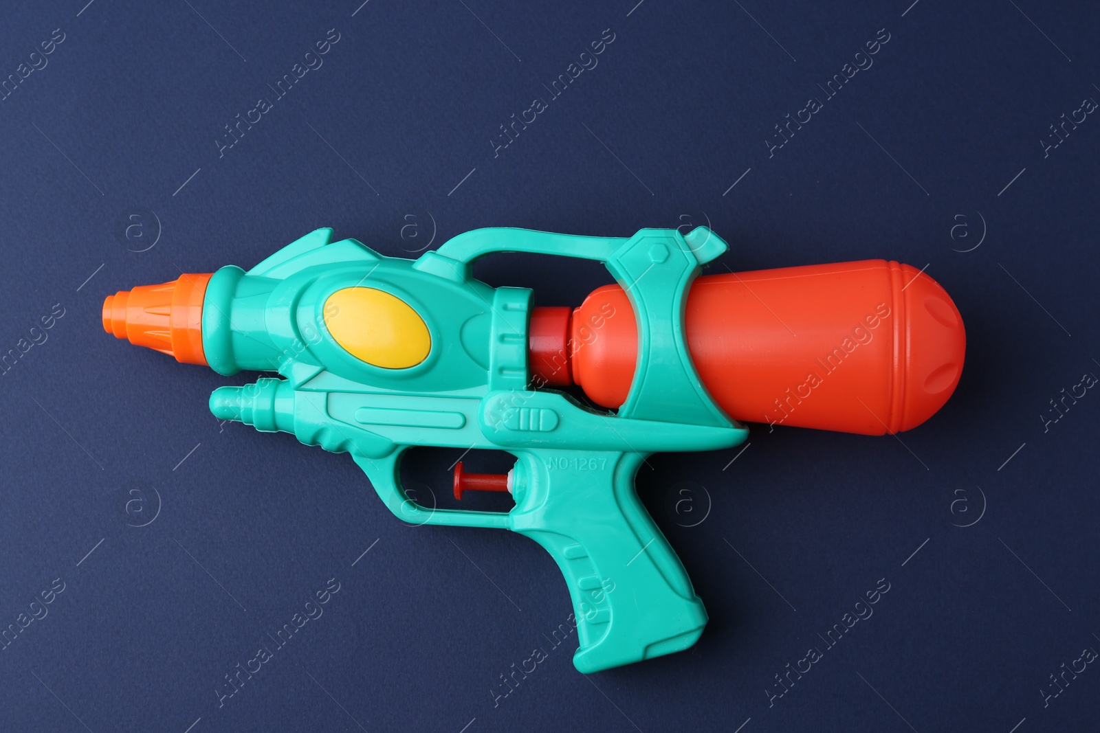 Bright plastic water gun on dark blue background, top view Photo of Bright plastic water gun on dark blue background, top view